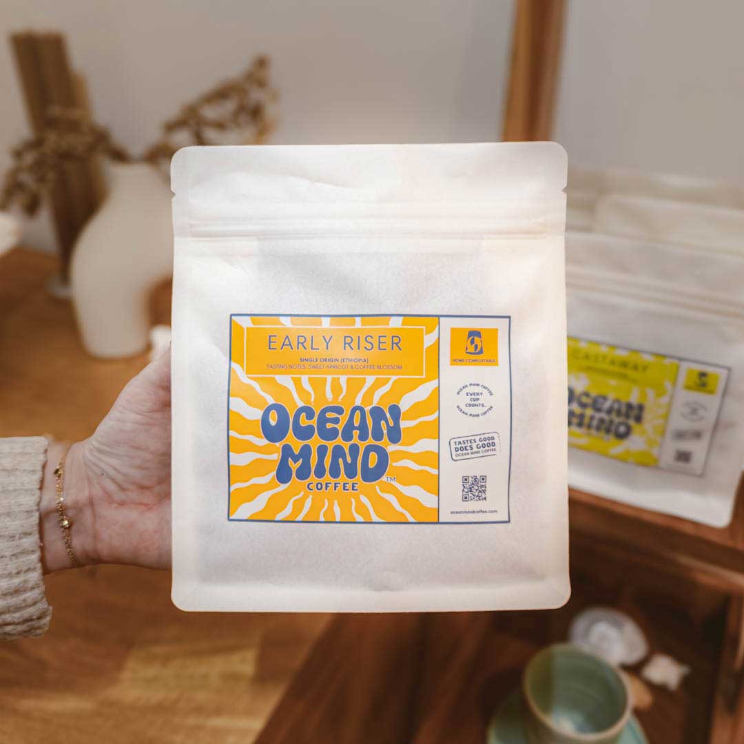 Hand holding a package of Early Riser Ocean Mind Coffee with an orange label