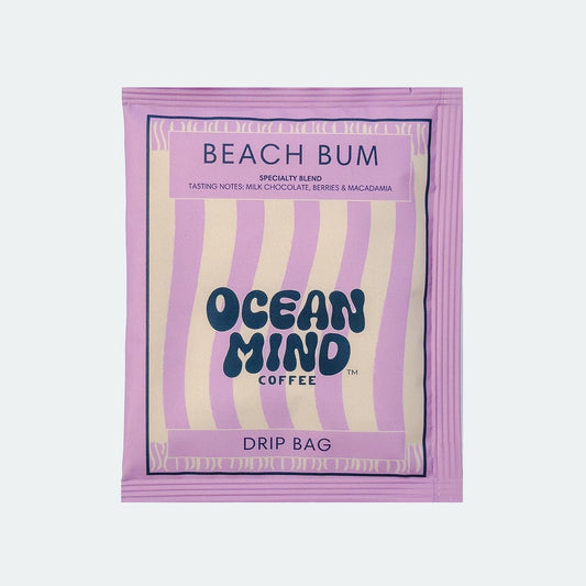 Ocean Mind Coffee 'Beach Bum' drip bag with purple design on a sea mist background