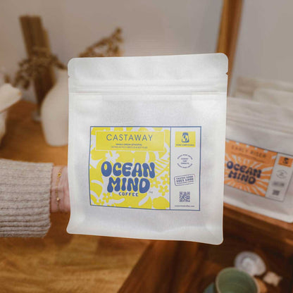 White coffee packaging with Castaway Ocean Mind Coffee label on a wooden surface