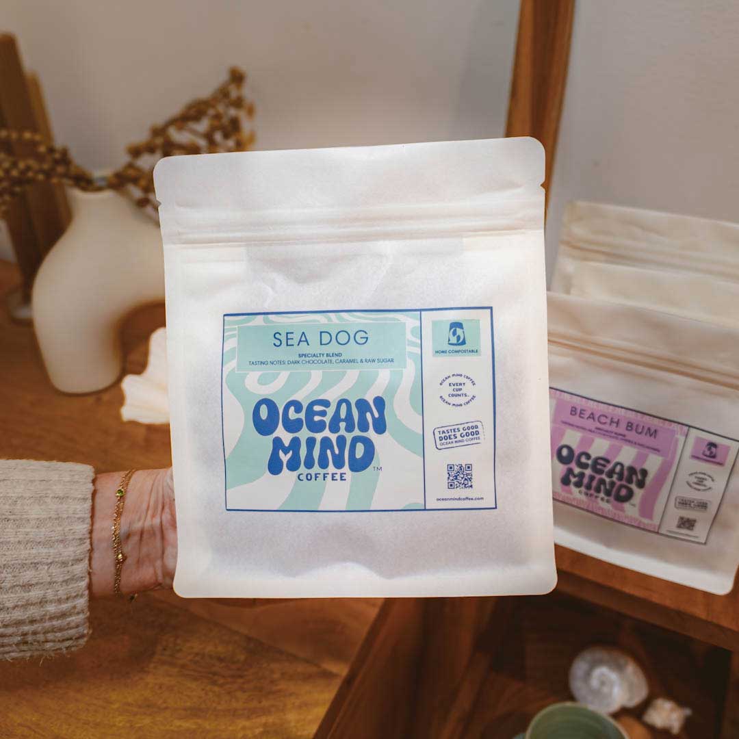 Hand holding a Sea Dog Ocean Mind Coffee package with another package in the background